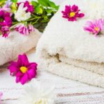 Two folded bath towels with some flowers on top